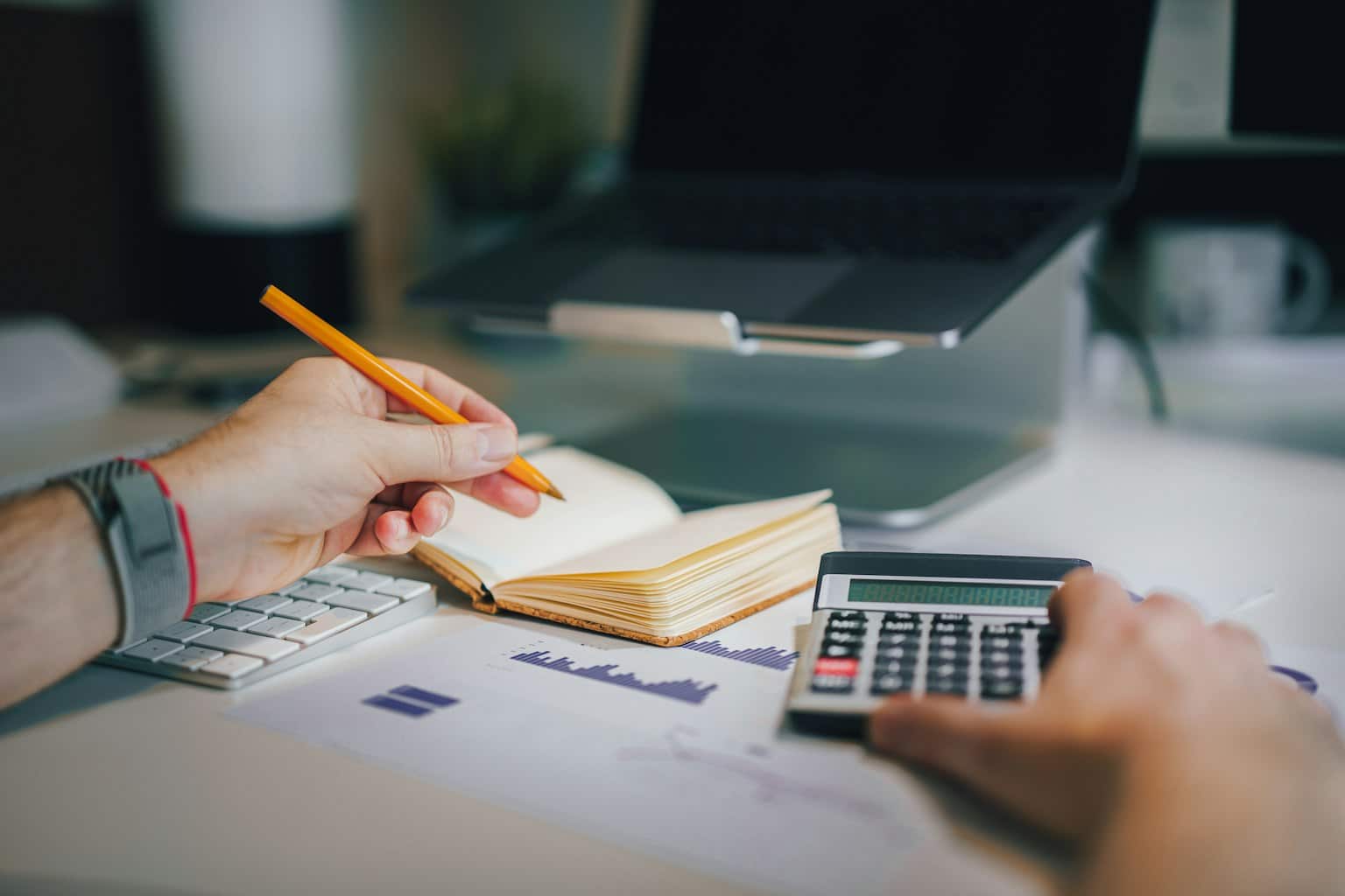Pessoa fazendo as contas com calculadora e caderno – Treinamento de Educação Financeira Pessoal